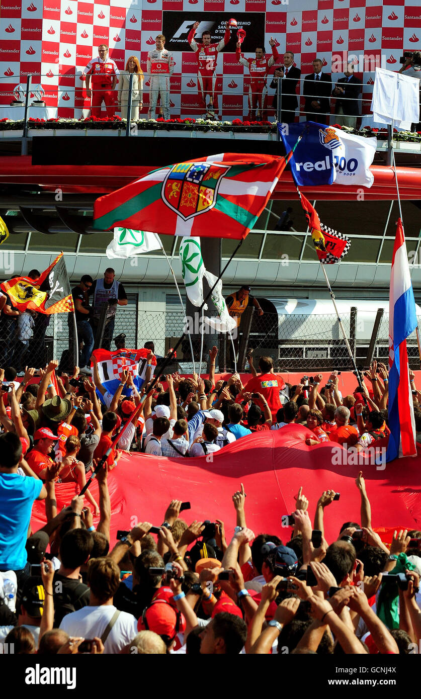 Ferrari's Fernando Alonso aus Spanien (oberhalb der Mitte) feiert auf dem Podium vor den massierten Fans nach dem Gewinn des italienischen Grand Prix auf dem Monza Circuit, Italien. Stockfoto