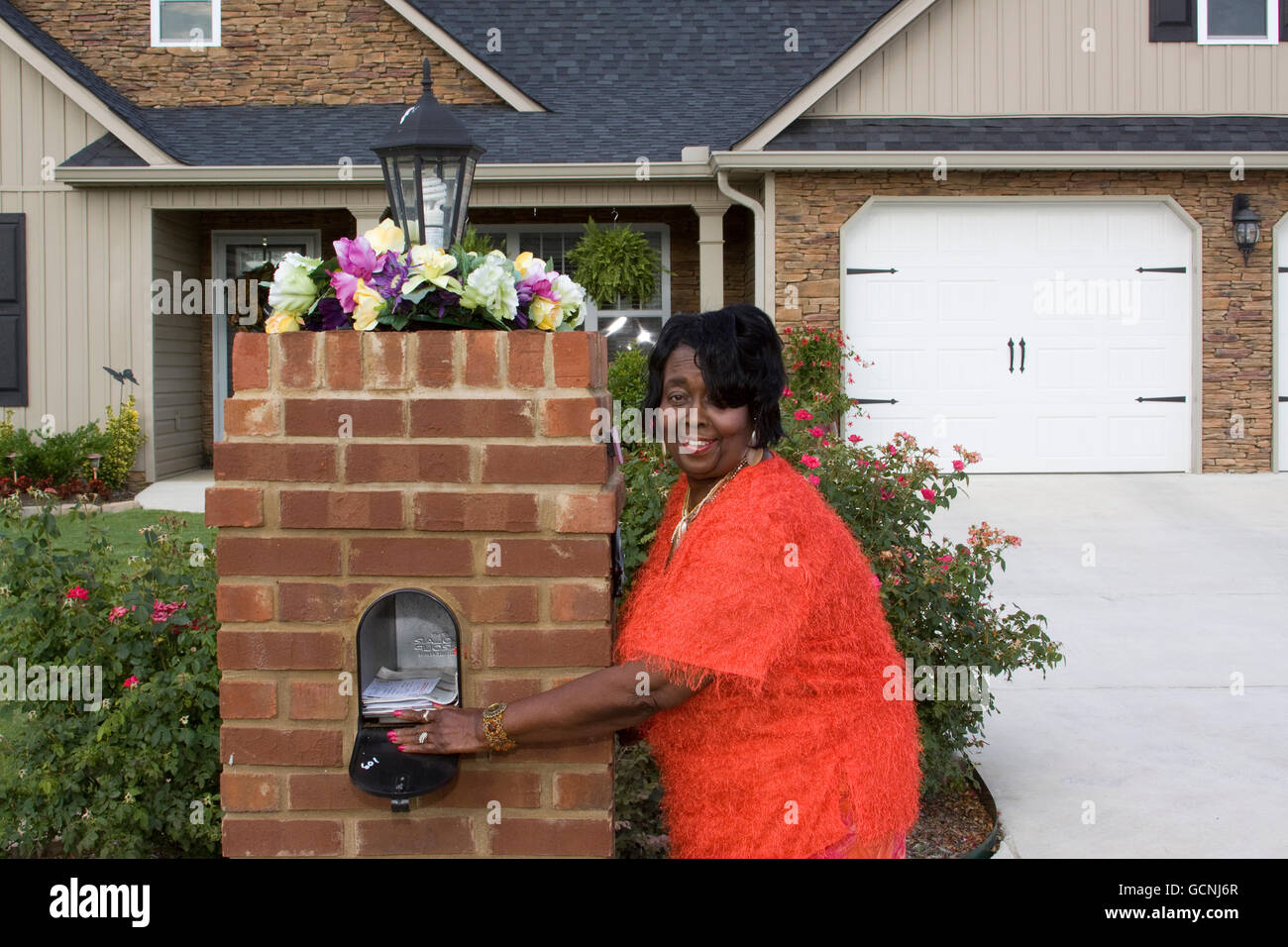 lächelnd schwarz senior Erwachsenen weiblichen Hausbesitzer bekommen ihre mail Stockfoto