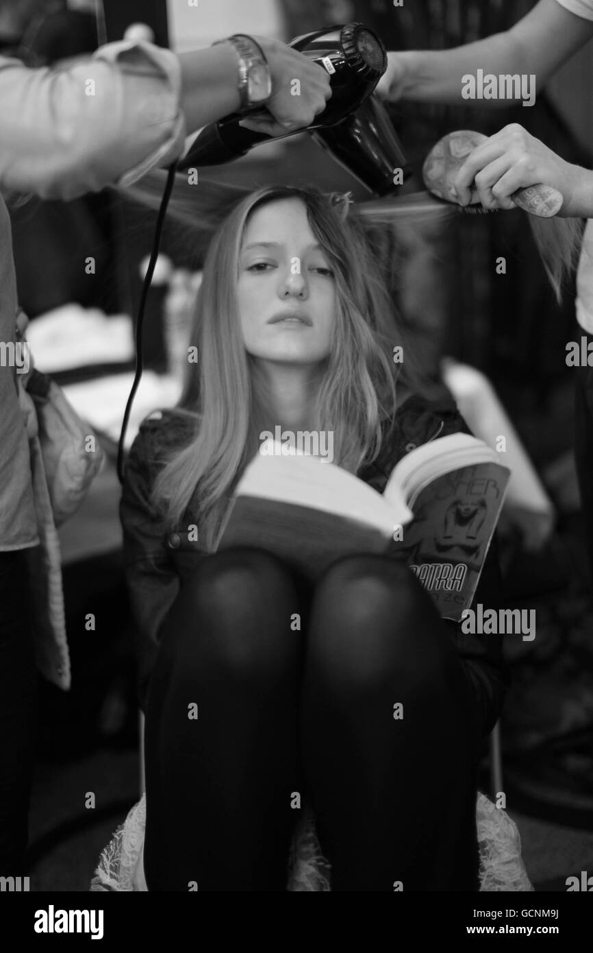 Ein Model liest ein Buch, während ihr Haar auf der Vivienne Westwood Red Label Show im Rahmen der London Fashion Week in London im Hintergrund getrocknet wird. PRESSEVERBAND Foto Datum: Sonntag, 19. September 2010. Bildnachweis sollte lauten: Katie Collins/PA Wire Stockfoto