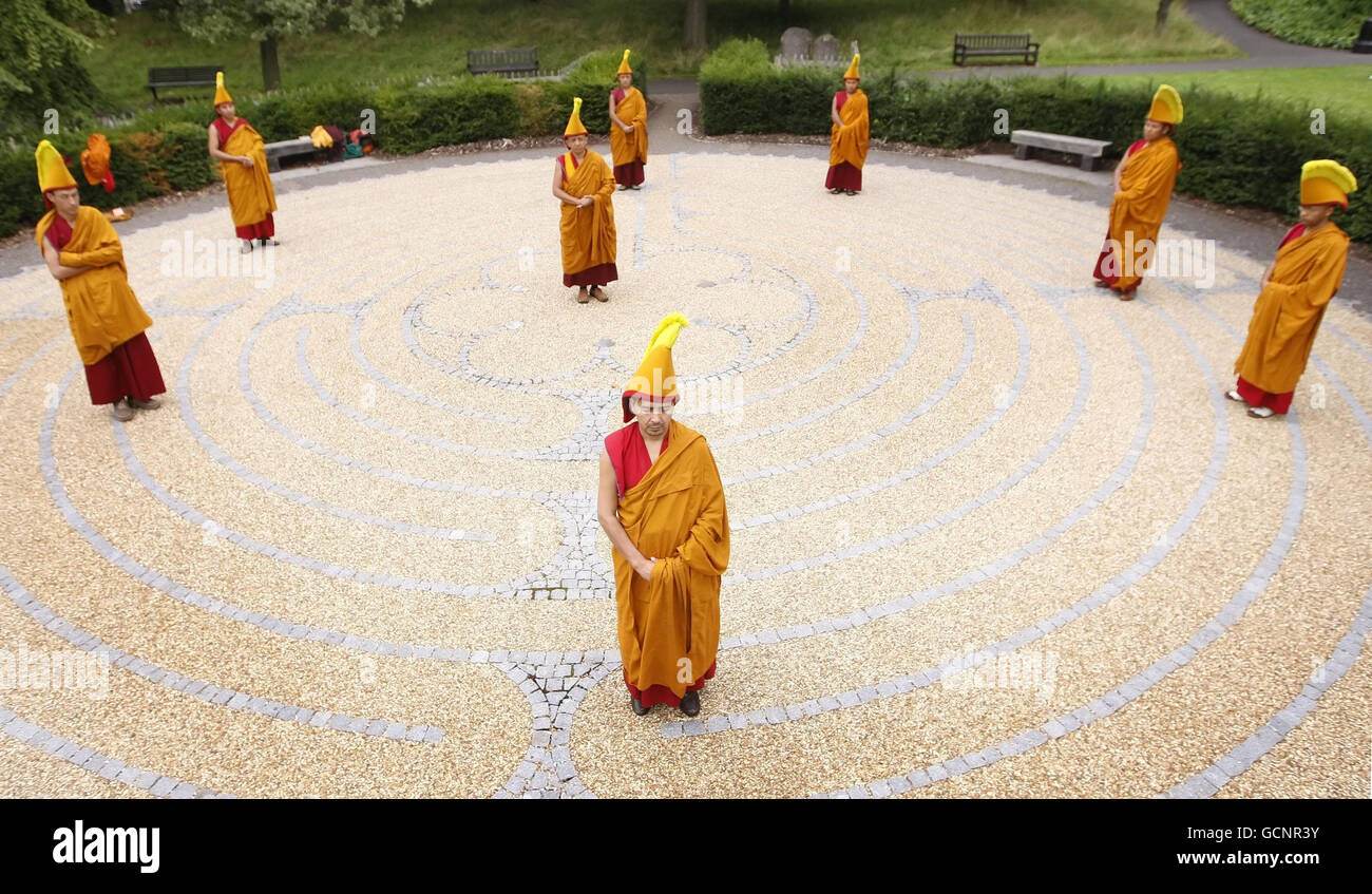 Buddhistische Mönche, die zeremonielle Kleidung tragen, gehen durch das Labyrinth der George Square Gärten in Edinburgh. Stockfoto