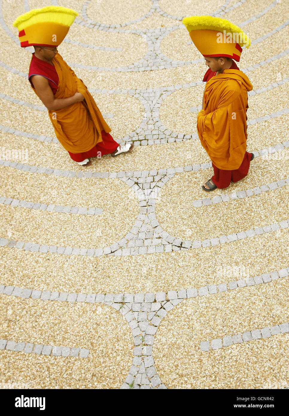 Buddhistische Mönche, die zeremonielle Kleidung tragen, gehen durch das Labyrinth der George Square Gärten in Edinburgh. Stockfoto