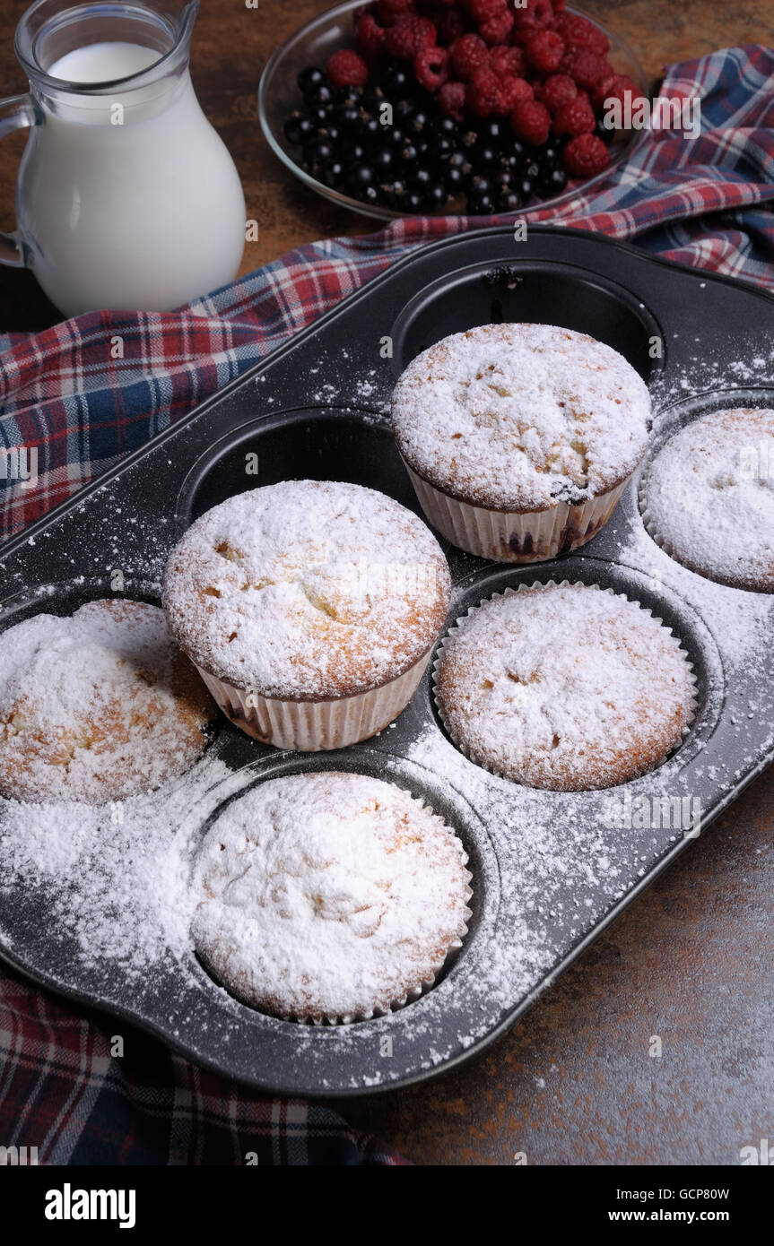Muffins Zucker Pulver in der Pfanne mit Milch und Beeren auf den Tisch Stockfoto