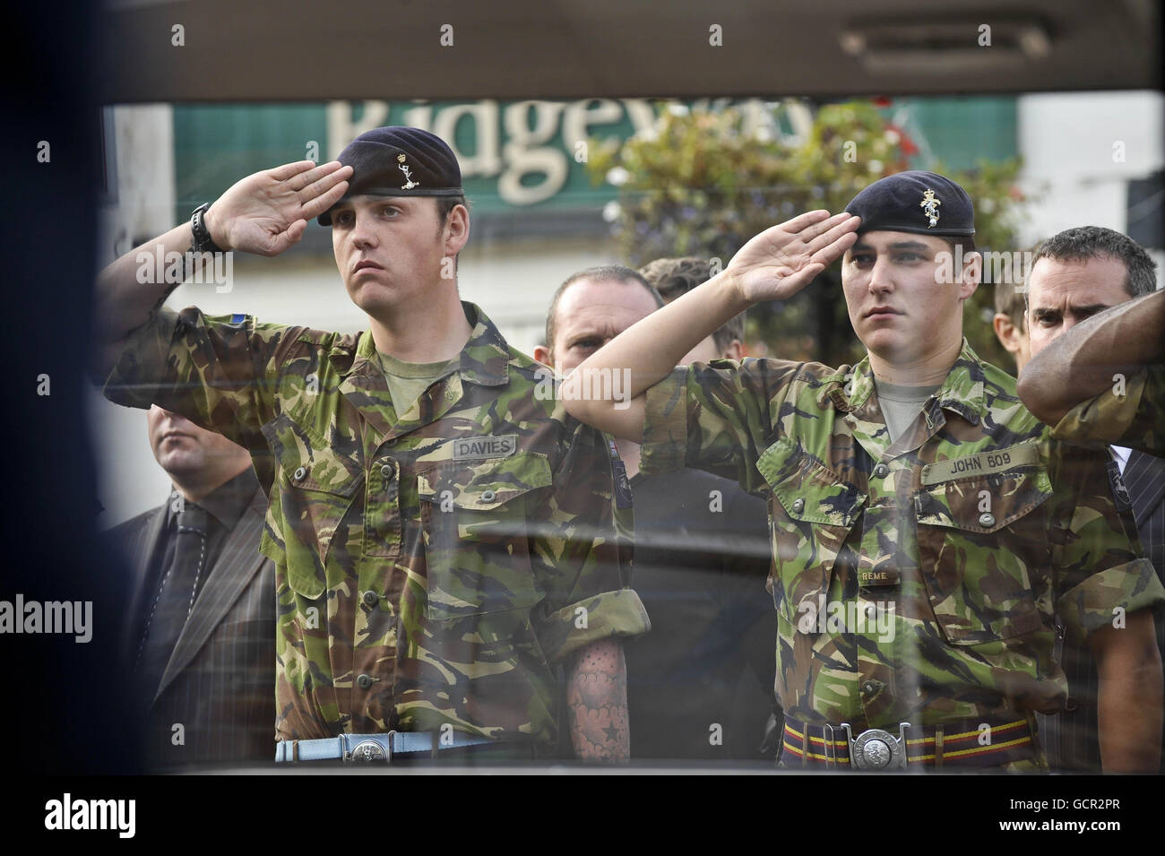 Soldaten grüßen, als der Sarg von Corporal Matthew Thomas nach seiner Rückführung nach RAF Lynham in eine vollgepackte Wootton Bassett High Street in Wiltshire eintrifft. Stockfoto