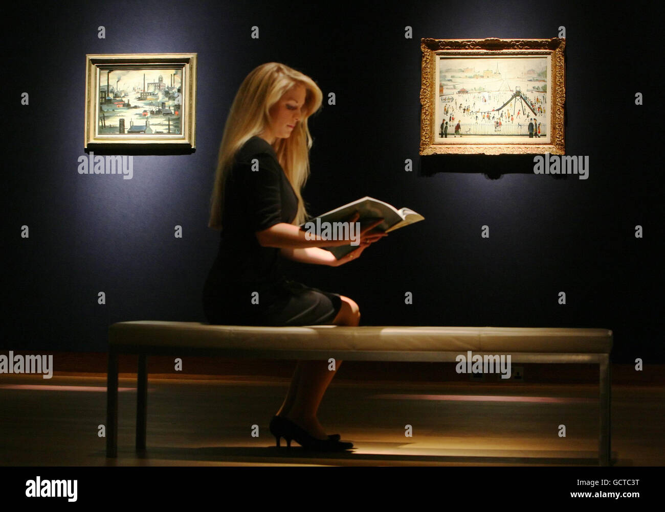 Ein Mitarbeiter von Christie (Name nicht angegeben) sieht sich einen Katalog für einen Verkauf von Werken von L S Lowry in London an. Stockfoto