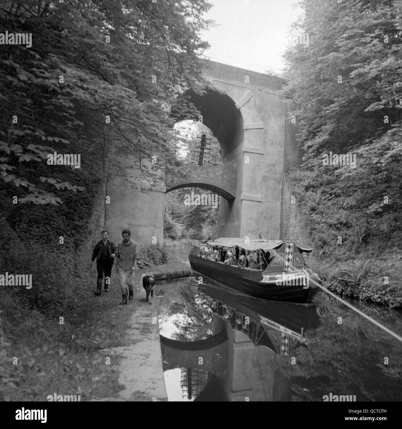 Eine Vergnügungsreise mit einem schmalen Boot führt entlang des Shropshire Union Canal, der unter einer kuriosen Doppelbrücke über die Newport nach Eccleshall Road in der Nähe von Gnosall, Staffordshire, geschleppt wird Stockfoto