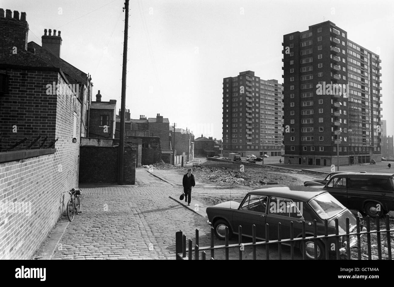 Schnell verschwindet die karge Gegend mit engen, gepflasterten Straßen, die lokal als „Hanky Park“ bezeichnet werden, in Salford, Lancashire, die den Hintergrund für den berühmten Roman „Love on the Dole“ von Walter Greenwood, der dort lebte, lieferte. Die winzigen zwei-oben- und zwei-unten-Häuser wurden durch Bulldozierung für neue Wolkenkratzerblocks wie die hier gezeigten, die über den Überresten der Vergangenheit emporragen, genutzt. Stockfoto