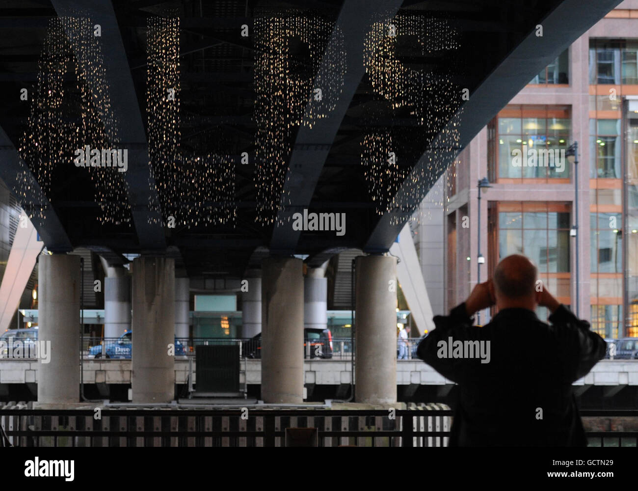 Pendler passieren einen Wasserfall aus Wörtern, der die am häufigsten gesuchten Wörter auf der Times-Website in Canary Wharf in London darstellt. Stockfoto