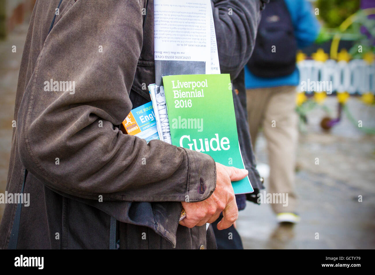Urlaubern und Geschäftsreisenden Mann mit Liverpool Biennale Reiseführer am Albert Dock, Merseyside, UK Stockfoto