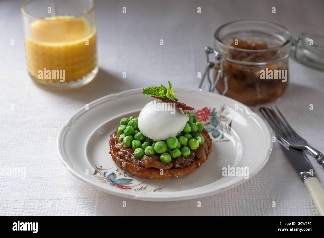 leckeres und gesundes Frühstück - Sandwich mit Zwiebelmarmelade, pochiertes Ei, Erbsen und Speck Stockfoto