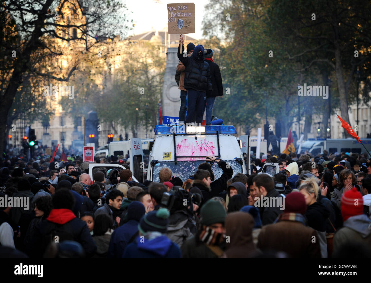 Ein Demonstranten bei einem studentenmarsch gegen staatliche Bildungskürzungen steht auf einem Polizeiwagen, der in London von Demonstranten umgeben ist. Stockfoto