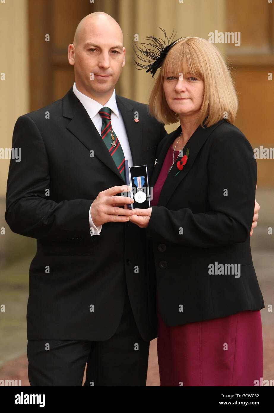 Steve und Angela Robinson, die Eltern von Rifleman Ross Robinson, mit seiner Queen's Gallantry Medal, die von Queen Elizabeth II. Posthum im Buckingham Palace in London verliehen wurde. Stockfoto