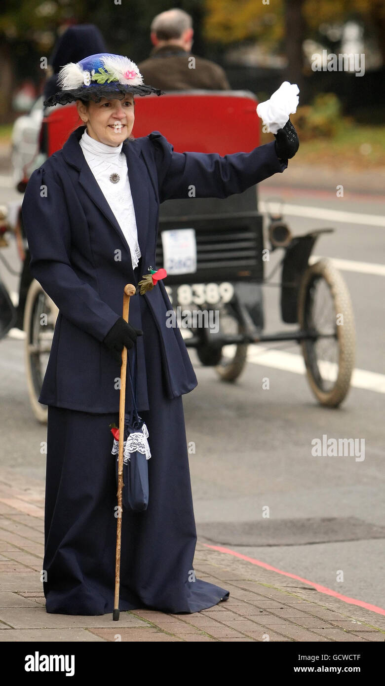 Eine Frau in historischen Kostümen winkt, als Teilnehmer des Veteran Car Run von London nach Brighton den Brixton Hill im Süden Londons erklimmten. Stockfoto