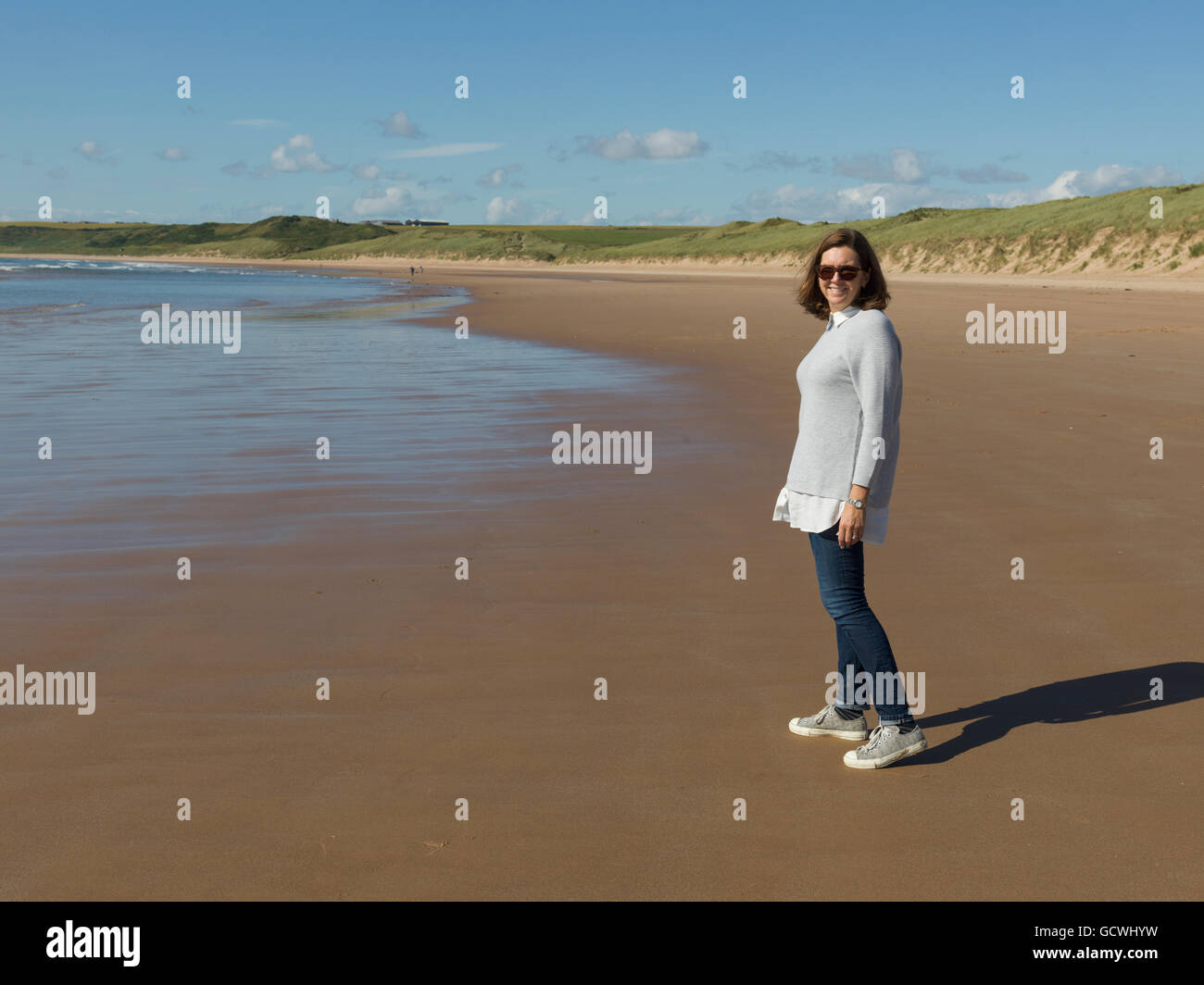 Eine Frau mit Sonnenbrille auf Cruden Bay Beach auf Cruden Bay stehen; Aberdeenshire, Schottland Stockfoto