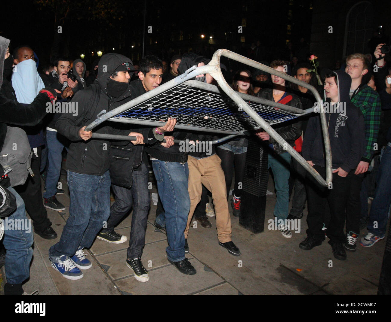 Während einer Demonstration gegen eine Erhöhung der Studiengebühren an der Universität in Whitehall, Westminster, im Zentrum von London, versuchen Demonstranten, eine Metallbarriere auf die Polizei zu werfen. Stockfoto