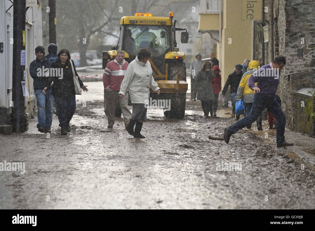 Die Menschen versuchen, den schweren Schlamm und Regen in den Straßen von Lostwithiel, Cornwall, zu vermeiden, wo Überschwemmungen verheerende Schäden angerichtet haben. Stockfoto