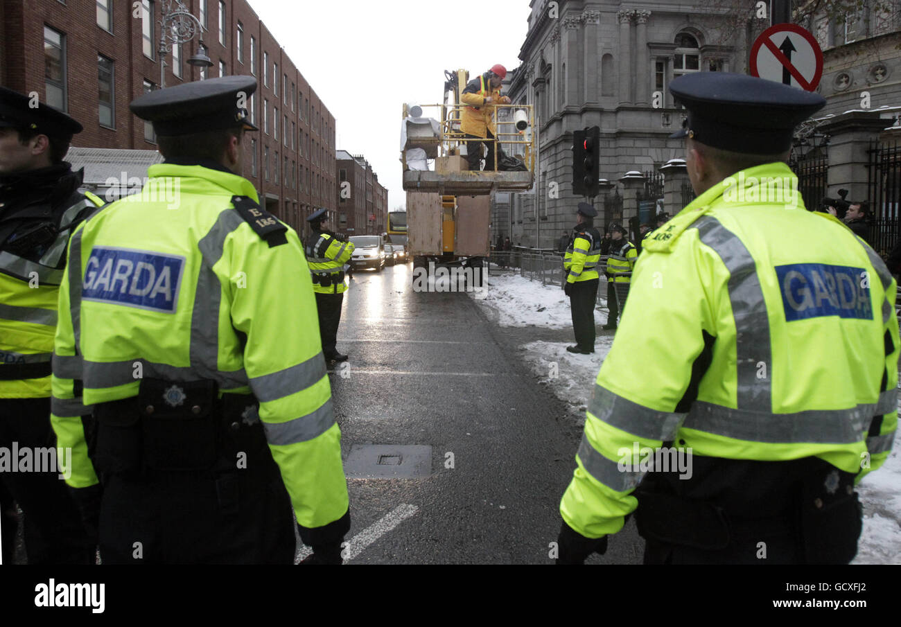 Ein Mann in einem Kirschbaum, der mit einer Reihe von Slogans bedeckt ist, die Politiker und den Bankensektor angreifen, um vor den Toren des Leinster House, Dublin, zu protestieren, unterhält sich am Budgettag mit gardai. DRÜCKEN SIE VERBANDSFOTO. Bilddatum: Dienstag, 7. Dezember 2010. Der Demonstrator parkte den Kran in der Nähe des Dails. Das Kontrollfeld wurde abgedichtet, wodurch gardai daran gehindert wurde, den Protestierenden wieder zu Boden zu bringen. Siehe Geschichte der PA IRISCHE Budgetproteste. Bildnachweis sollte lauten: Niall Carson/PA Wire Stockfoto