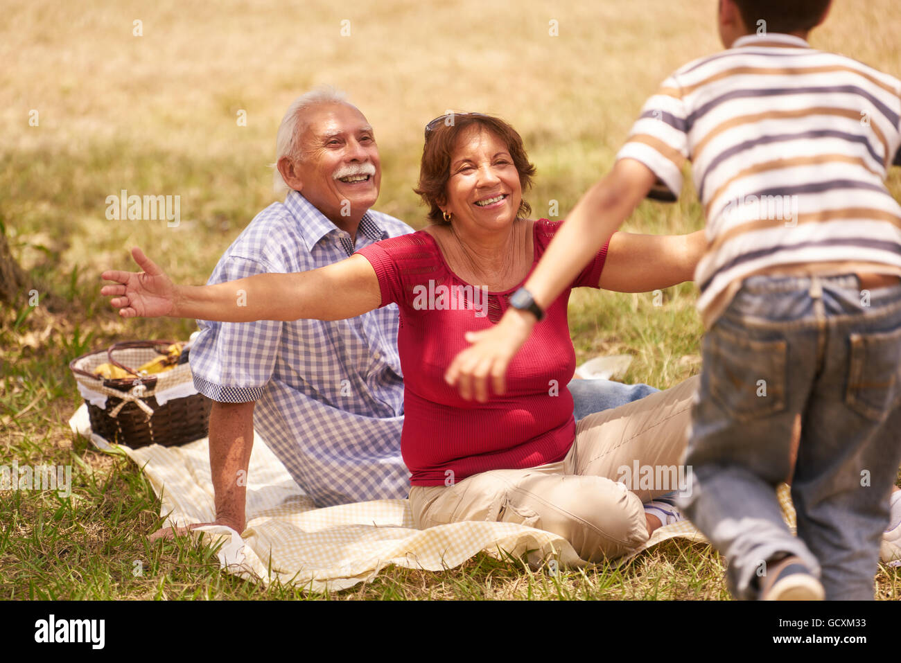 Alte Menschen, älteres Paar, älterer Mann und Frau. Outdoor-Familie, die Spaß mit glücklichen Opa und Oma umarmt junge am Picknick Stockfoto