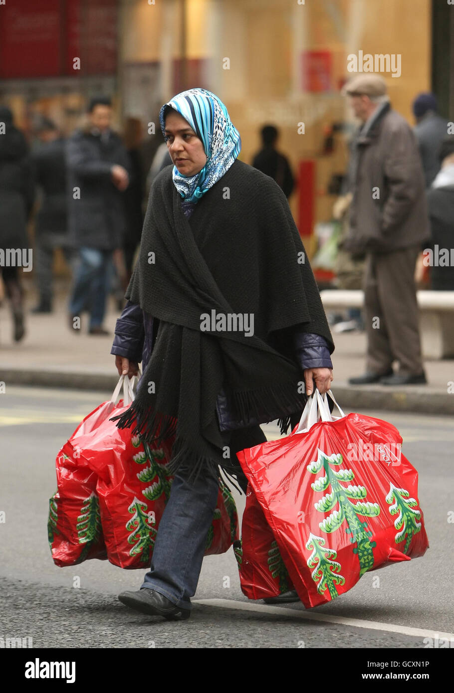 Verkäufe nach Weihnachten. Ein Shopper trägt seine Taschen in der Oxford Street im Zentrum von London. Stockfoto