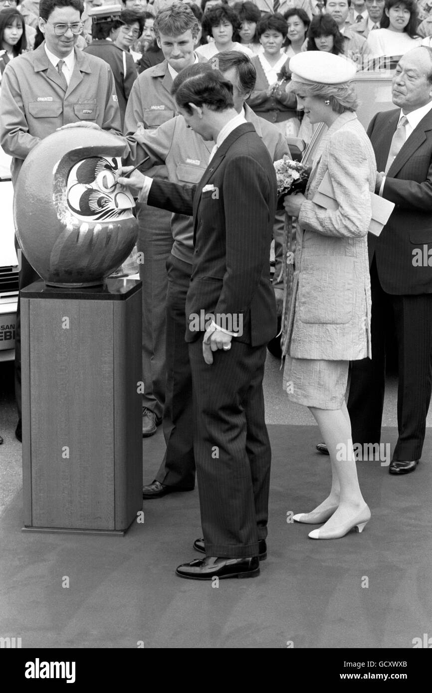 Der Prinz von Wales wirft ein Auge auf eine Daruma-Puppe, während die Prinzessin von Wales bei ihrem Besuch in einer Nissan-Fabrik über seine Schulter schaut. Die Prinzessin trägt ein Outfit des Designers Bruce Oldfield. Stockfoto