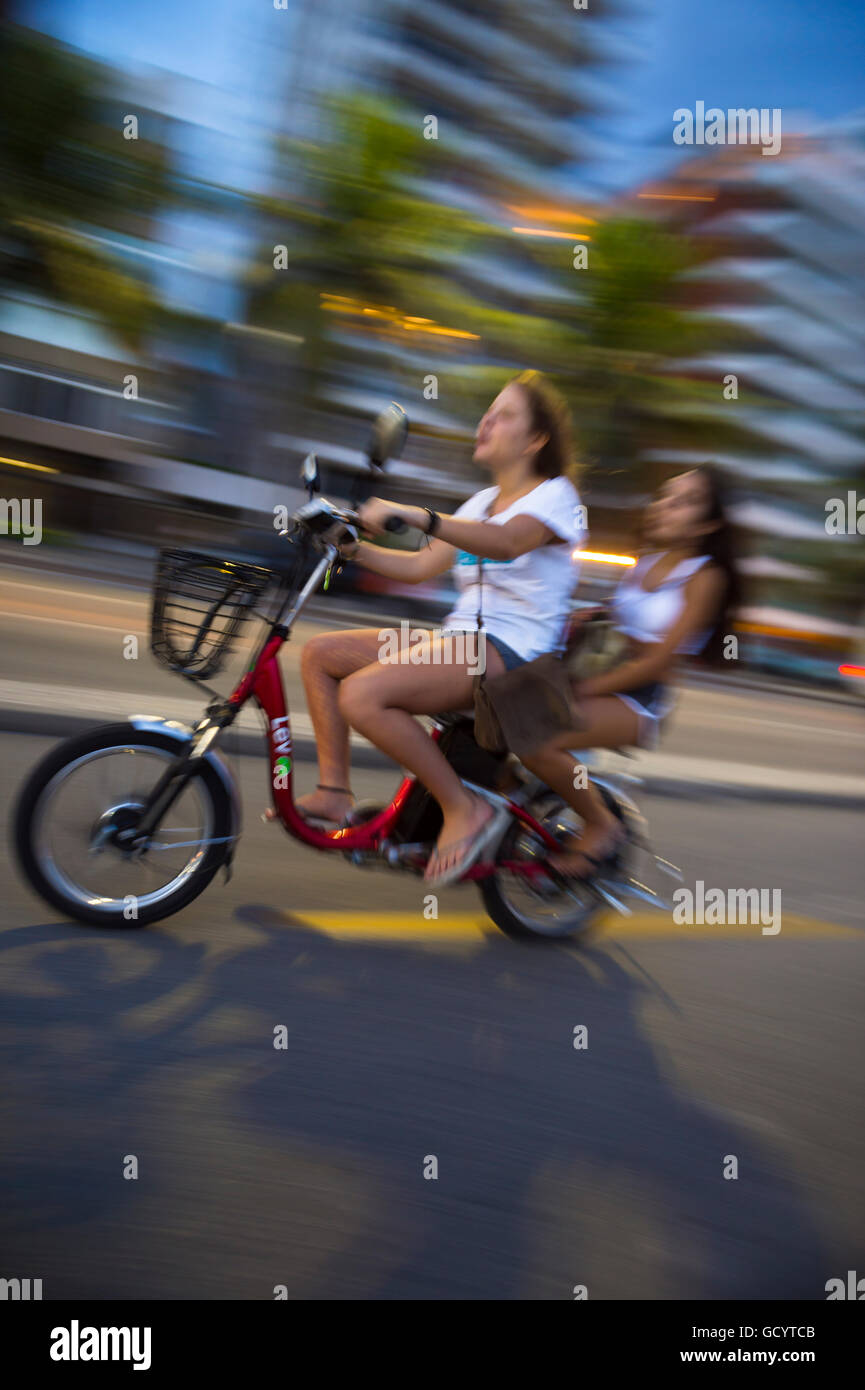 RIO DE JANEIRO - 6. März 2016: Junge Brasilianer fahren e-Bike in Bewegungsunschärfe Ipanema Beach direkt am Strand unterwegs. Stockfoto