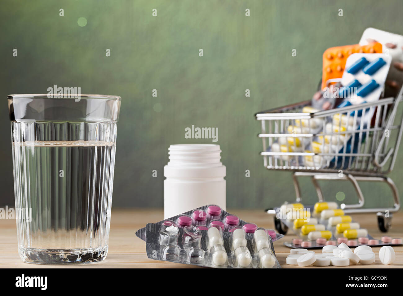 Satz von Glas Wasser und Pille-Blister-Verpackungen auf Holztisch Stockfoto