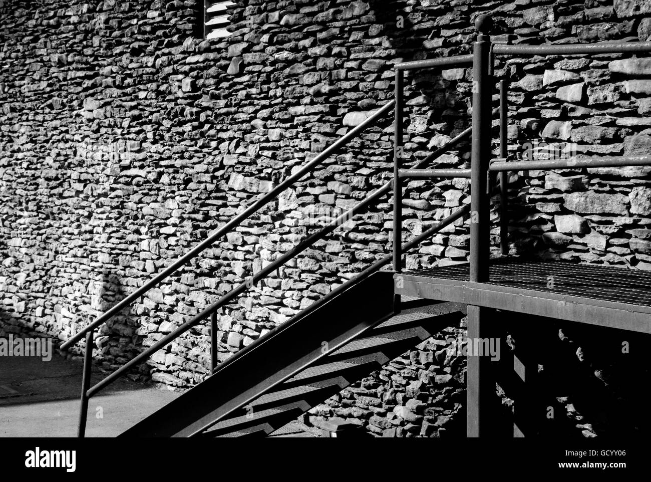 Eine Vintage massive handgemachte Felswand des Bauens mit Metall-Treppe auf mysteriöse Weise strahlt monochromatische Textur Stockfoto Eine Vintage massive handgemachte Felswand des Bauens mit Metall-Treppe auf mysteriöse Weise strahlt monochromatische Textur Stockfoto