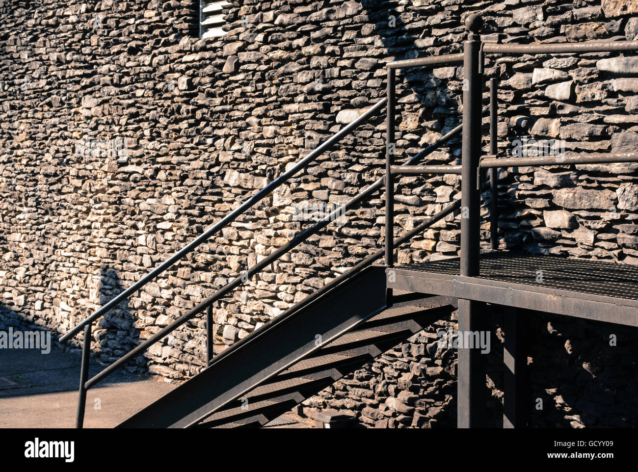 Eine Vintage massive handgemachte Felswand des Bauens mit Metall-Treppe auf mysteriöse Weise strahlt monochromatische Textur Stockfoto Eine Vintage massive handgemachte Felswand des Bauens mit Metall-Treppe auf mysteriöse Weise strahlt monochromatische Textur Stockfoto