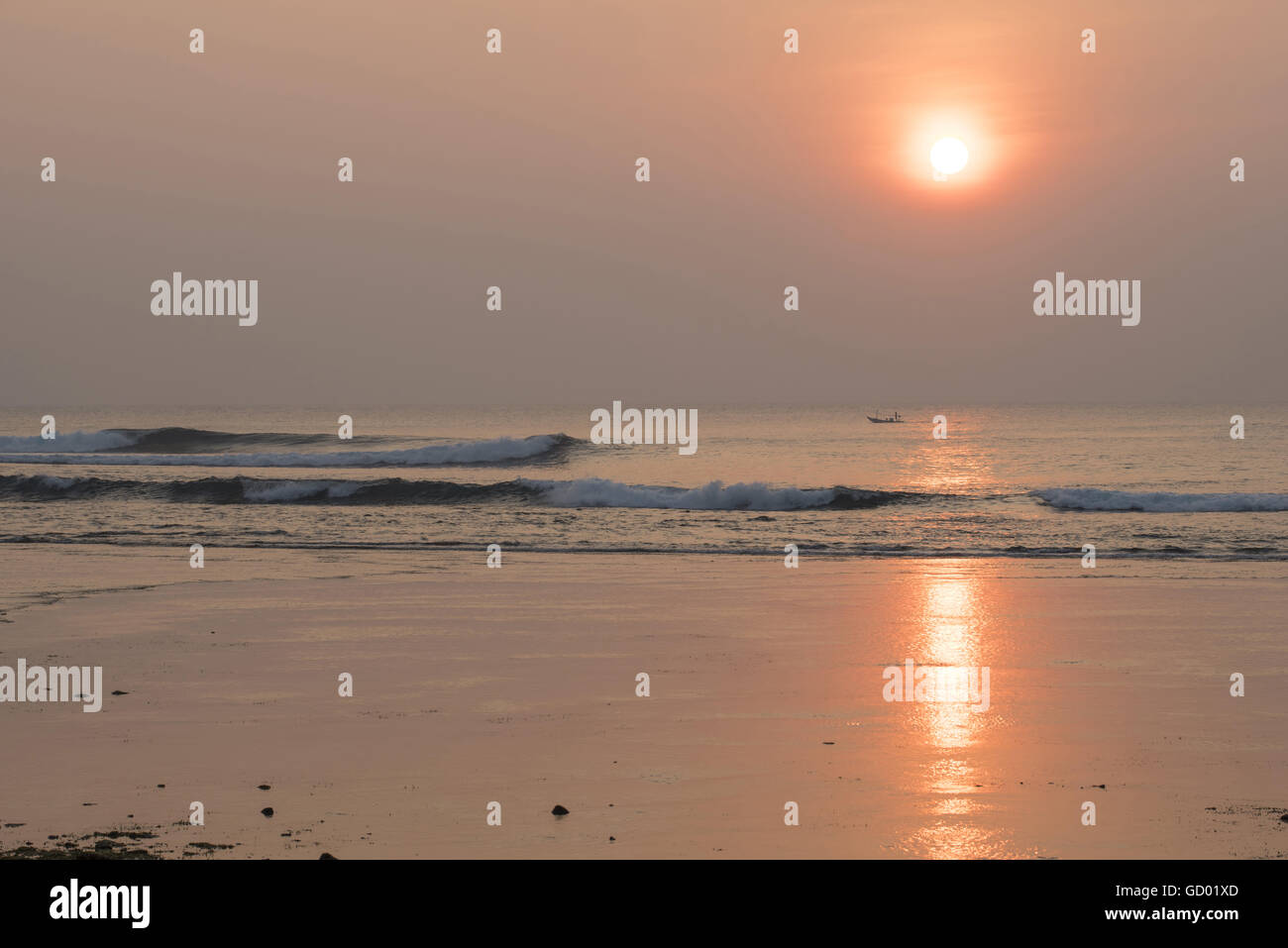 Friedliche Sommerlandschaft, Sonnenuntergang über Strandküste mit Angelboot/Fischerboot am Horizont. Stockfoto