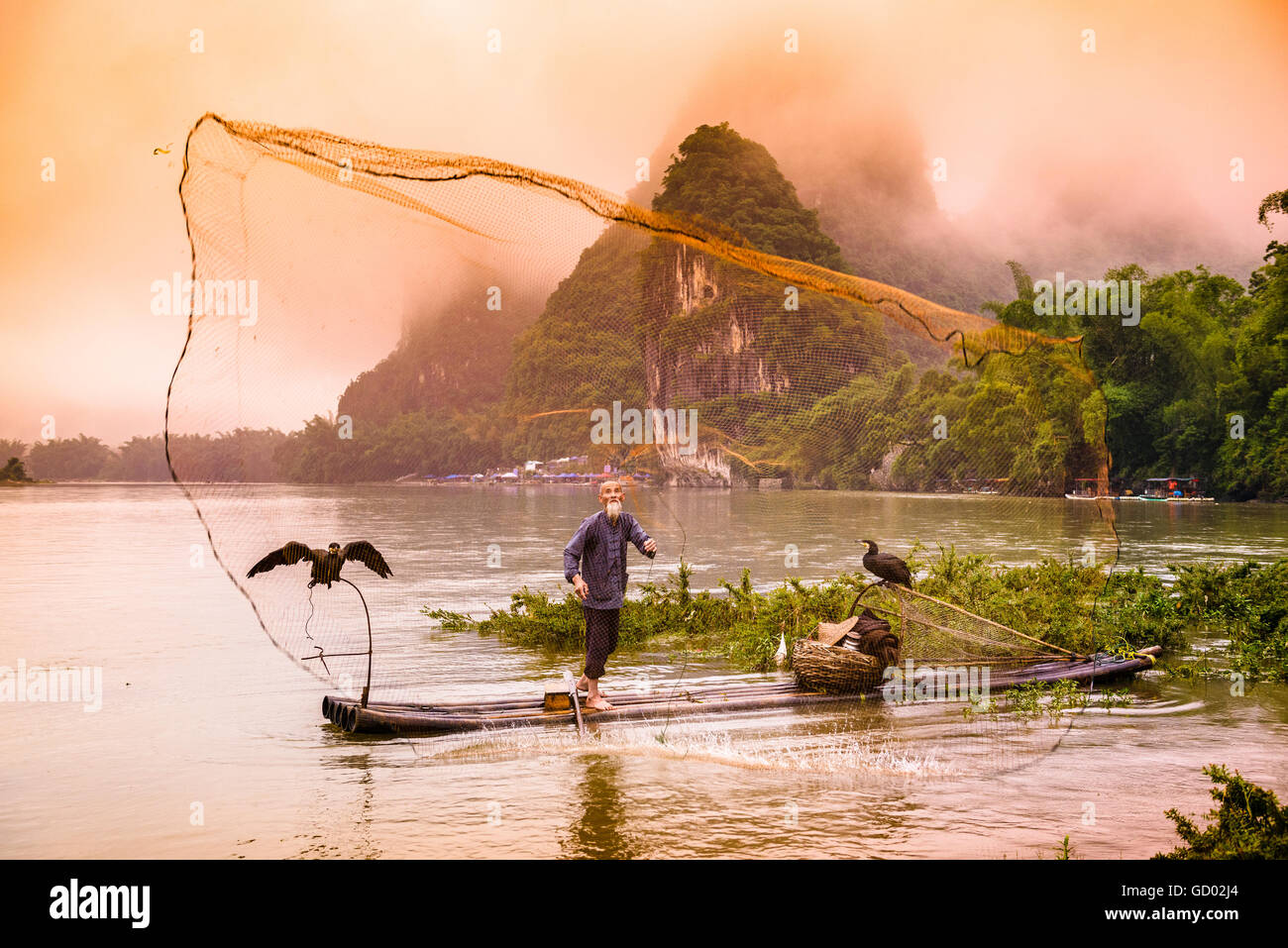 Traditionelle chinesische Kormoran Fischer wirft ein Netz auf dem Li-Fluss in Yangshuo, China. Stockfoto