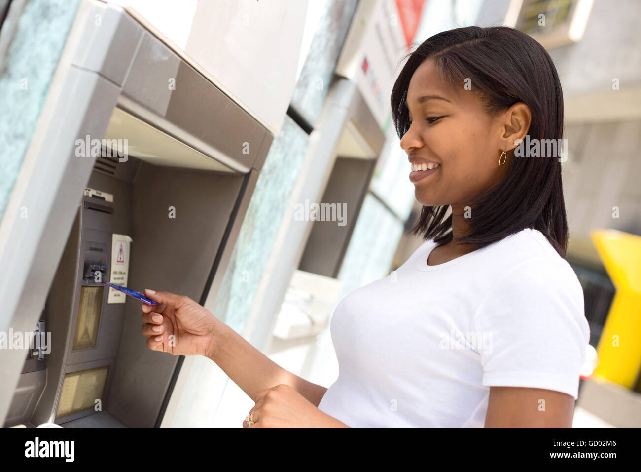 junge Frau an den Geldautomaten Geld abheben Stockfoto