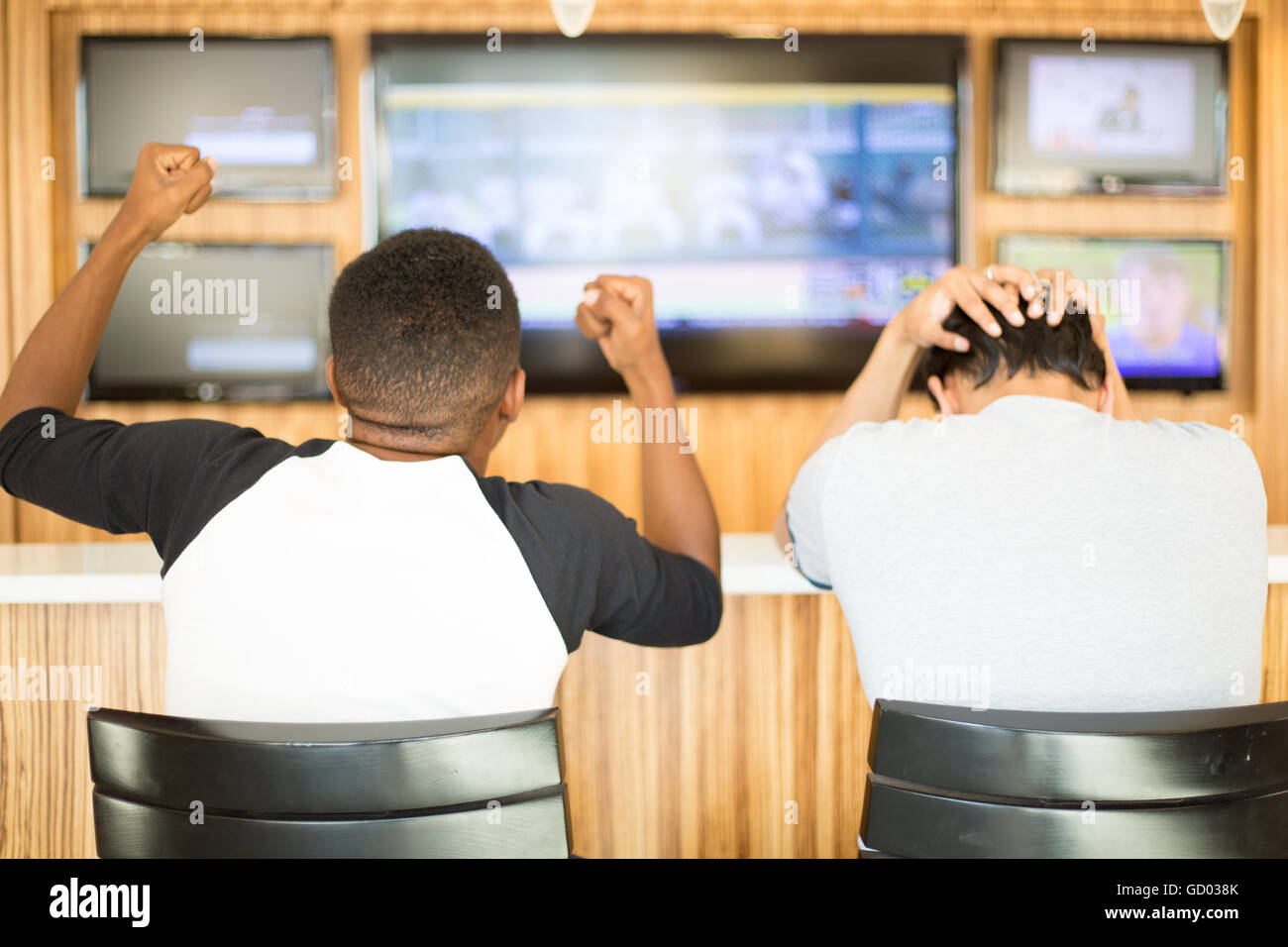 Closeup Portrait, zwei Männer, ein Sport-Spiel im Fernsehen anschauen.  Ein Mann freut sich, andere Kerl fühlt sich schrecklich. Teamgeist-Konzept Stockfoto