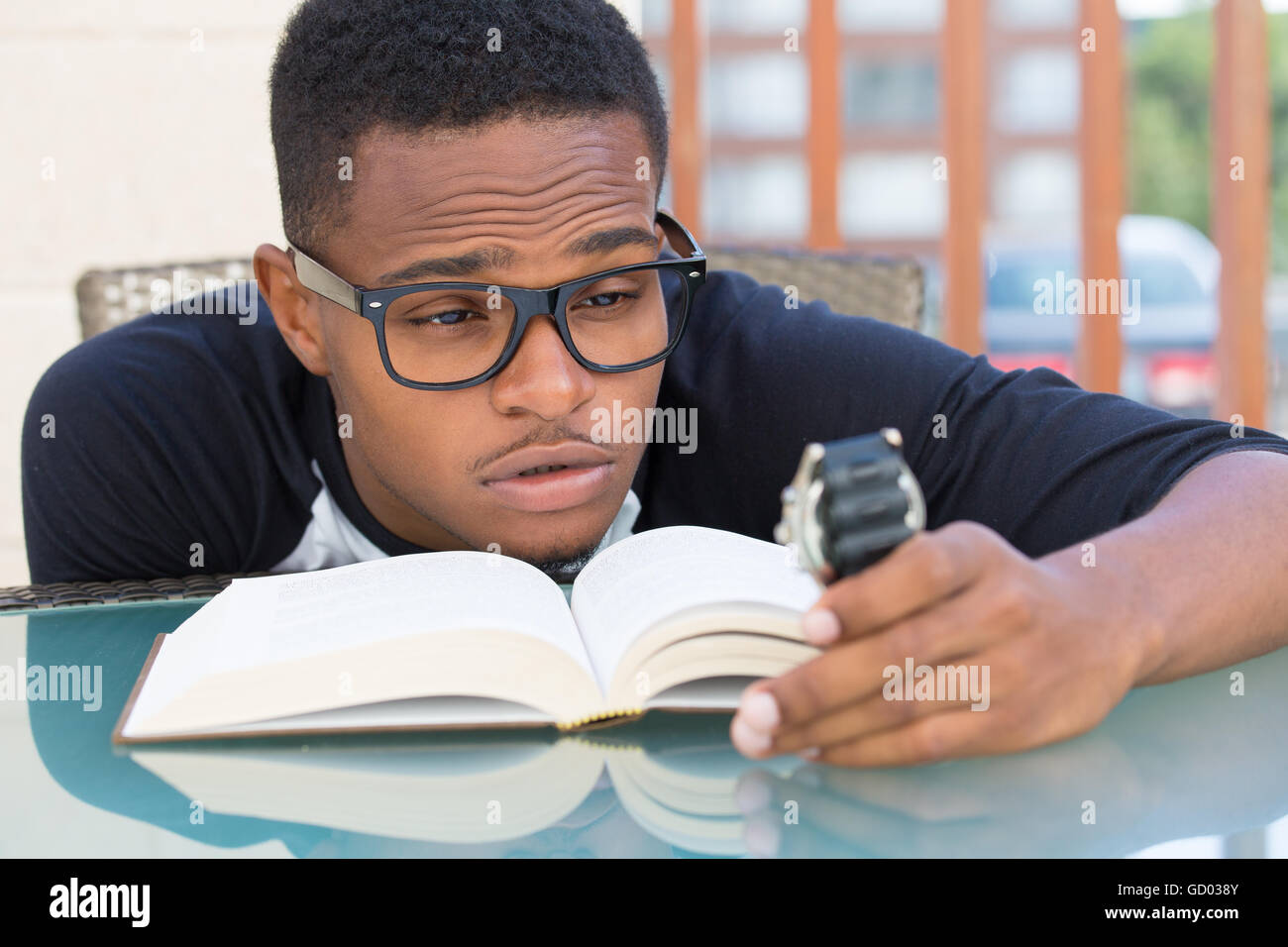 Closeup Portrait, nerdy junge Mann in großen schwarzen Gläsern halten sehen, fallen sehr müde des Lesens, isoliert im freien außerhalb Stockfoto
