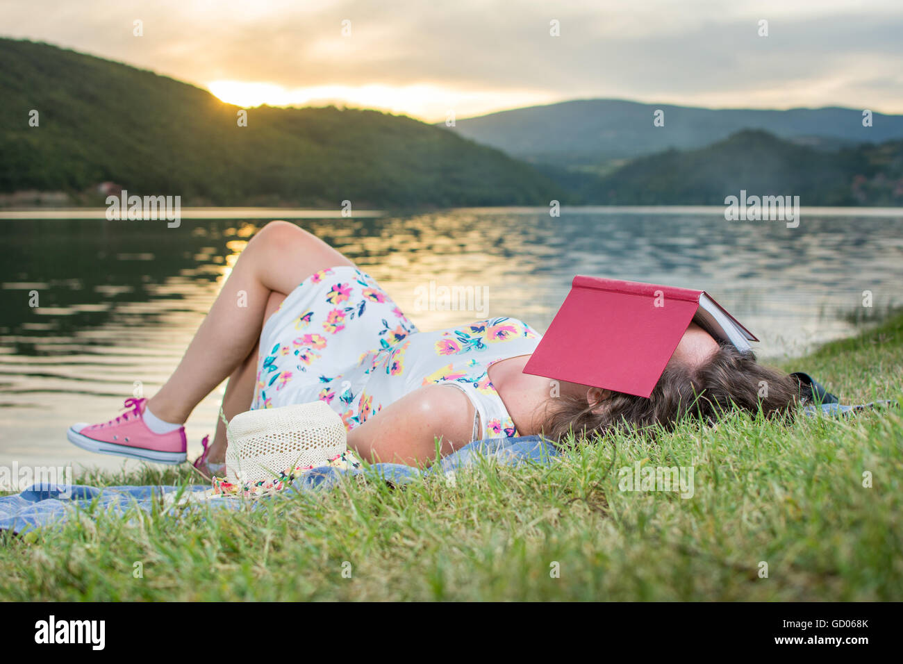 Junge Frau schläft mit einem Buch am See. Solo-Entspannung Stockfoto