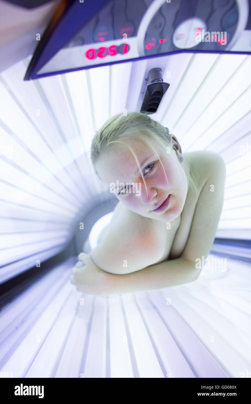 Hübsche junge Frau, die ihre Haut in ein modernes Solarium bräunen Stockfoto