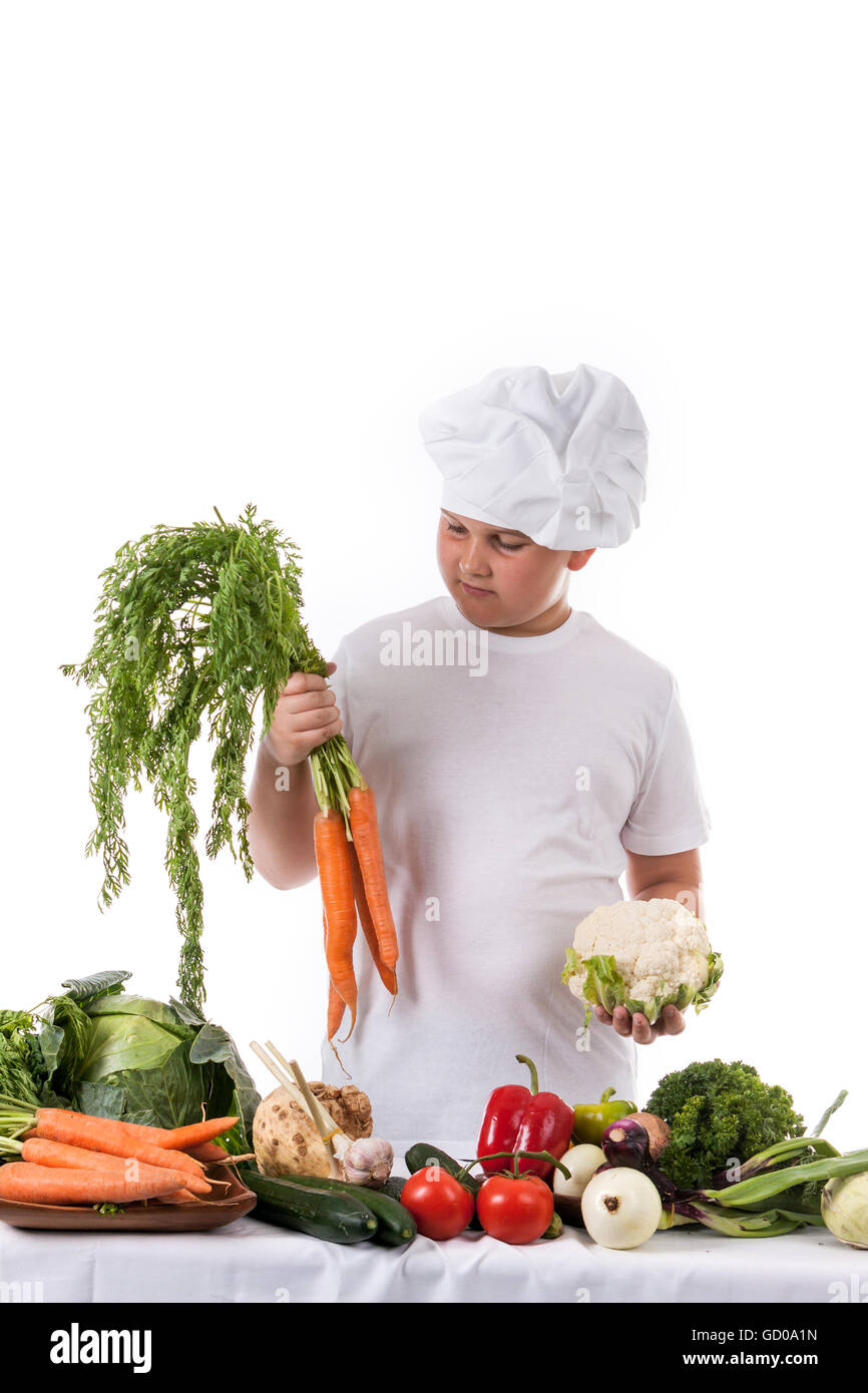 Ein kleiner Junge als Chef Koch machen Salat, Kochen mit Gemüse. Isoliert auf weiss. Stockfoto