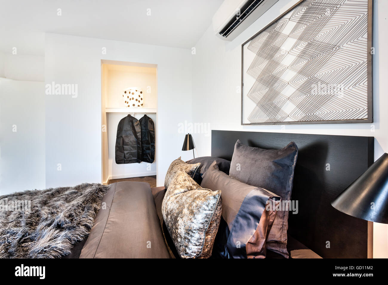 Nahaufnahme von einem modernen Schlafzimmer glänzende Kissen auf einem Bett mit Pelz Bettdecken neben eine Waschküche Stockfoto