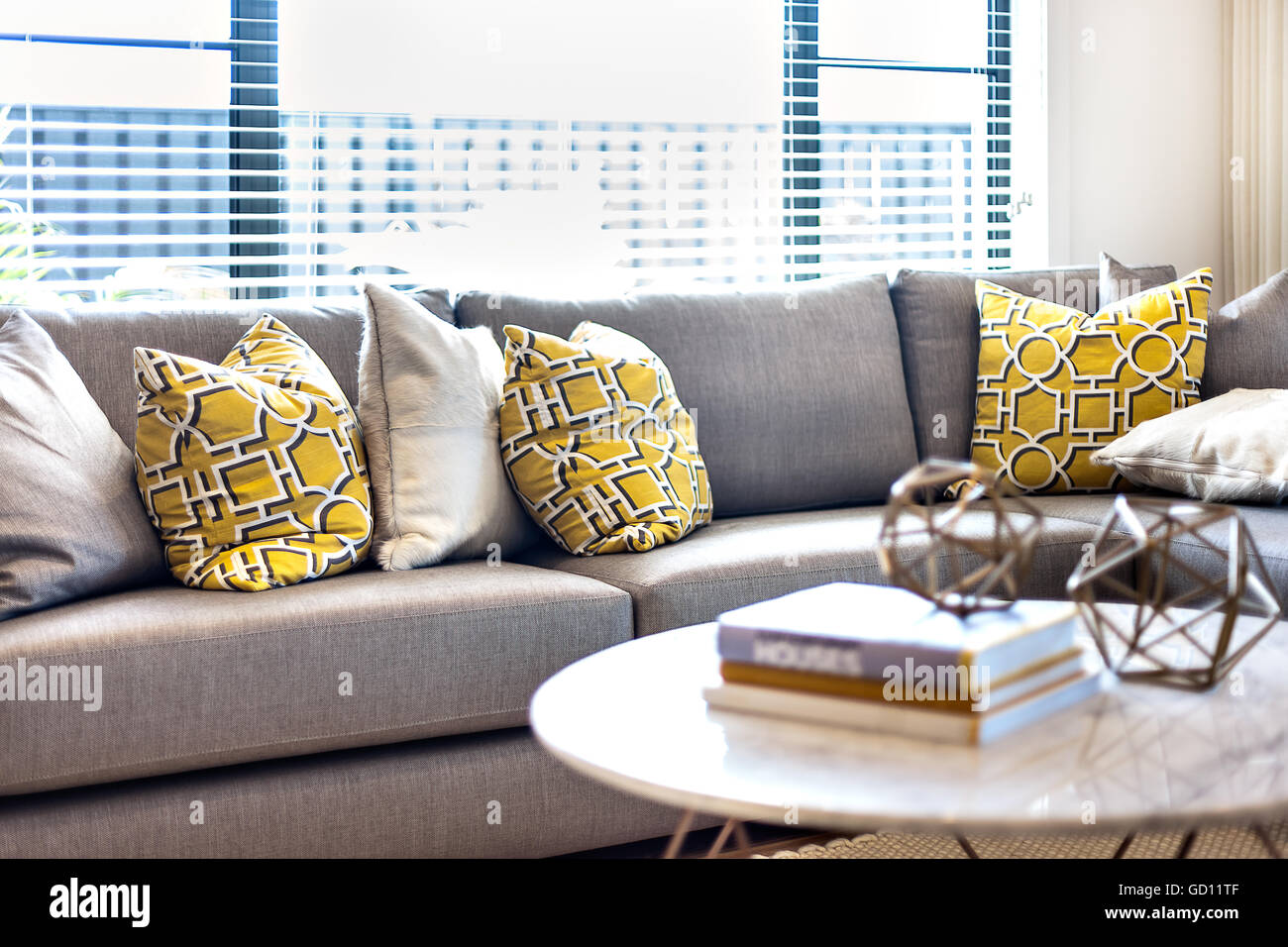 Gelbe und graue Farbe Kissen auf dem Sofa neben ein Fenster, das das  Sonnenlicht in den Raum mit unscharfen Bücher und Phantasie breitet sich  Stockfotografie - Alamy