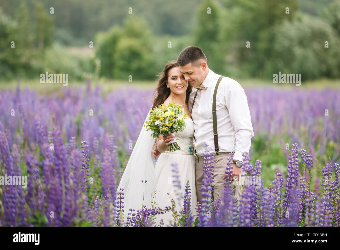 Glückliches Hochzeitspaar umarmt im Feld lupine Stockfoto