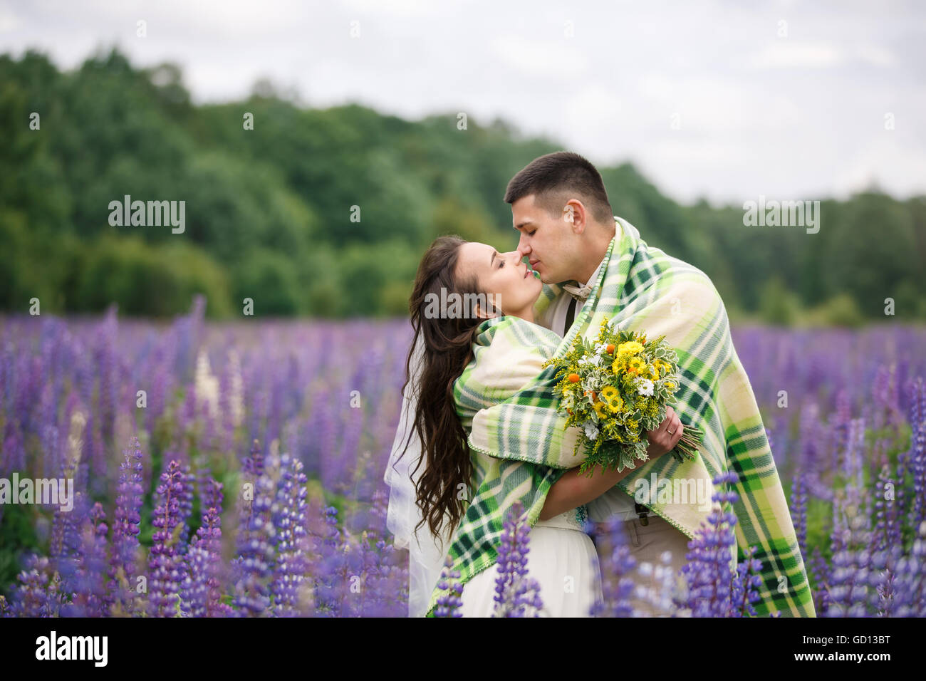 Glückliches Hochzeitspaar umarmt im Feld lupine Stockfoto