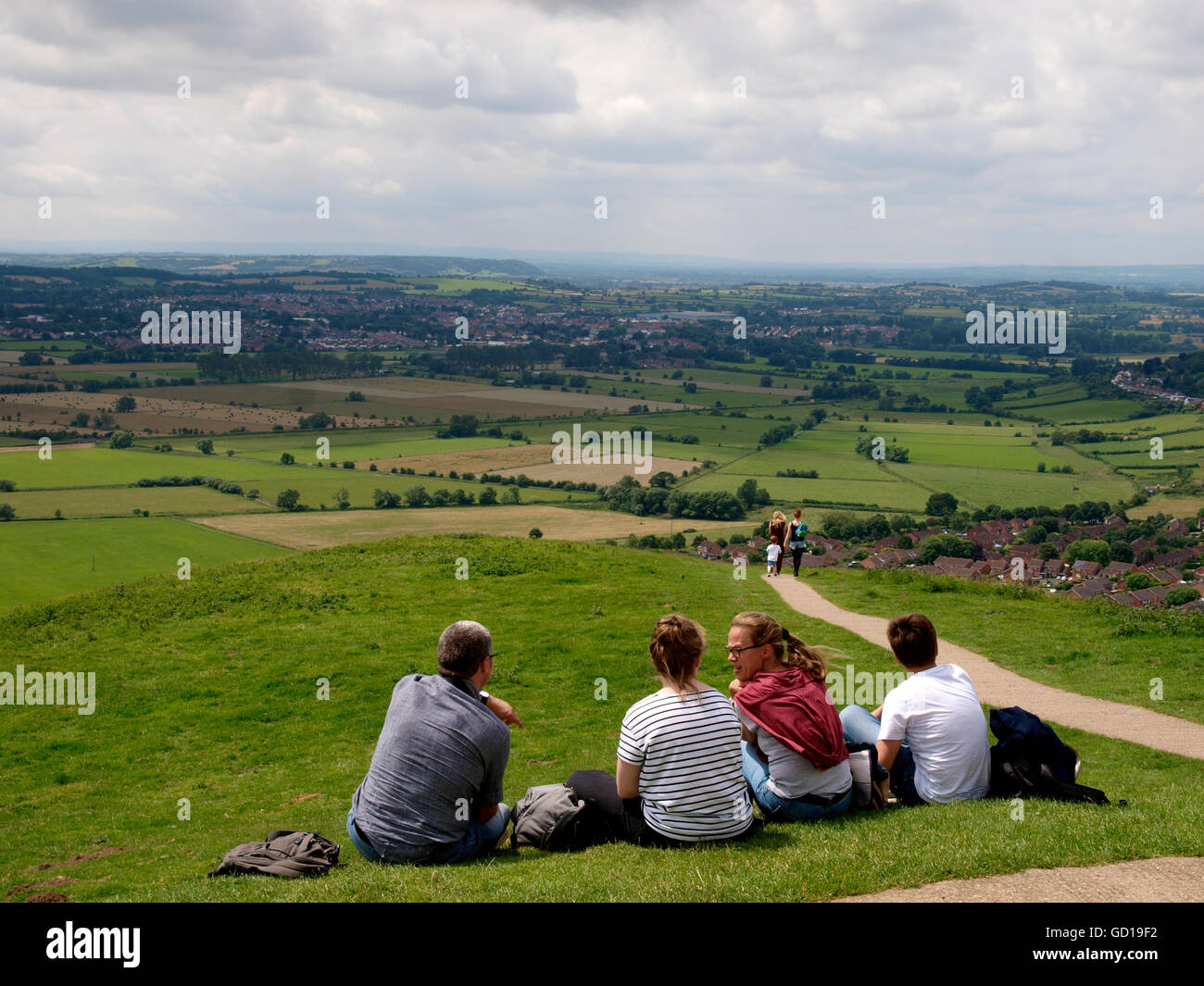 Familie saß an der Spitze des Glastonbury Tor betrachten über den Somerset Levels, Glastonbury, Somerset, Großbritannien Stockfoto