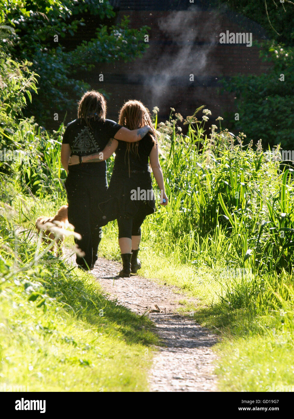 Junges Paar auf einem Wanderweg zu Fuß, Runde Arme einander in der Sommersonne, Devizes, Wilts, Großbritannien Stockfoto