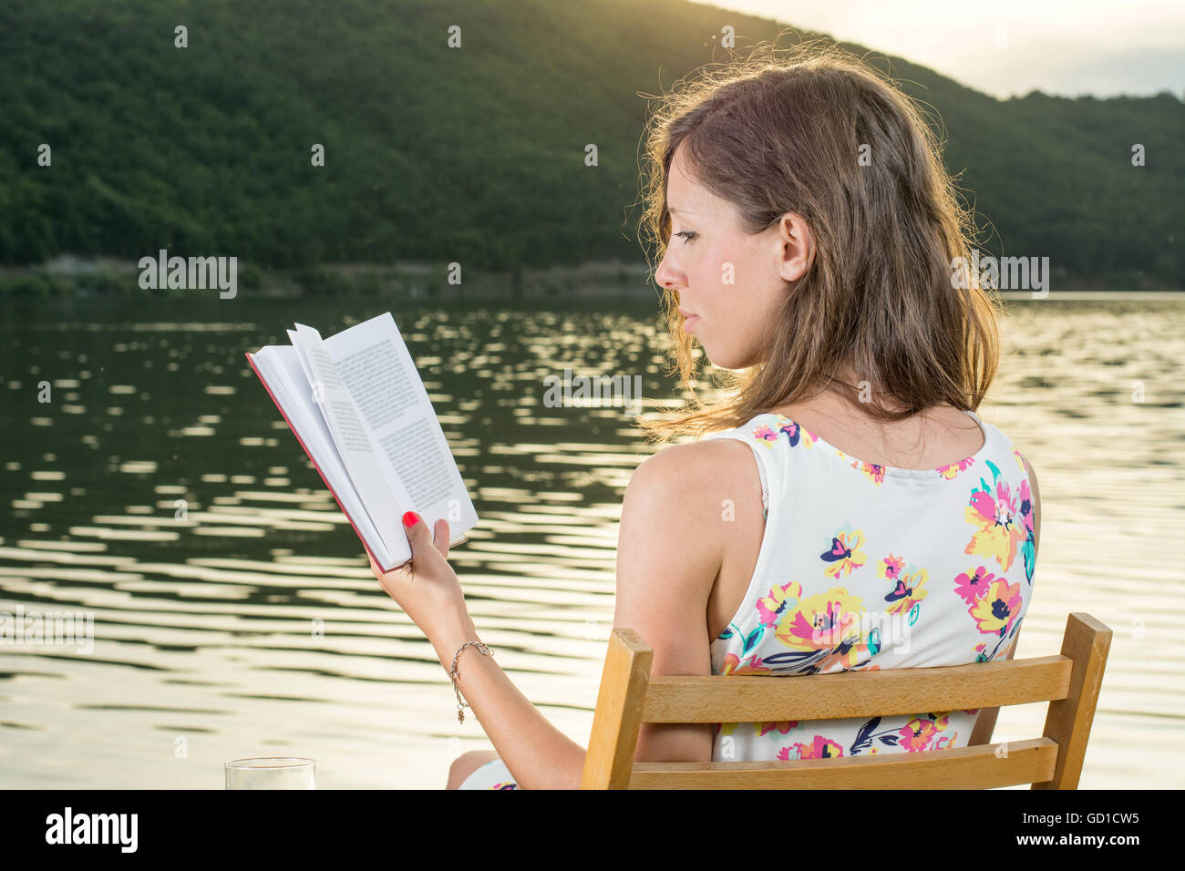 Junge Frau, die ein Buch am See Stockfoto