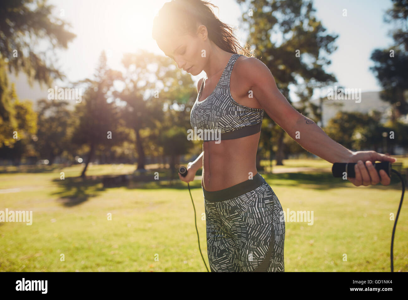 Außenaufnahme einer Frau in Sportbekleidung, die draußen in einem Park mit Seilspringen trainiert. Fitnesstraining-Frau mit Sprungseil Stockfoto