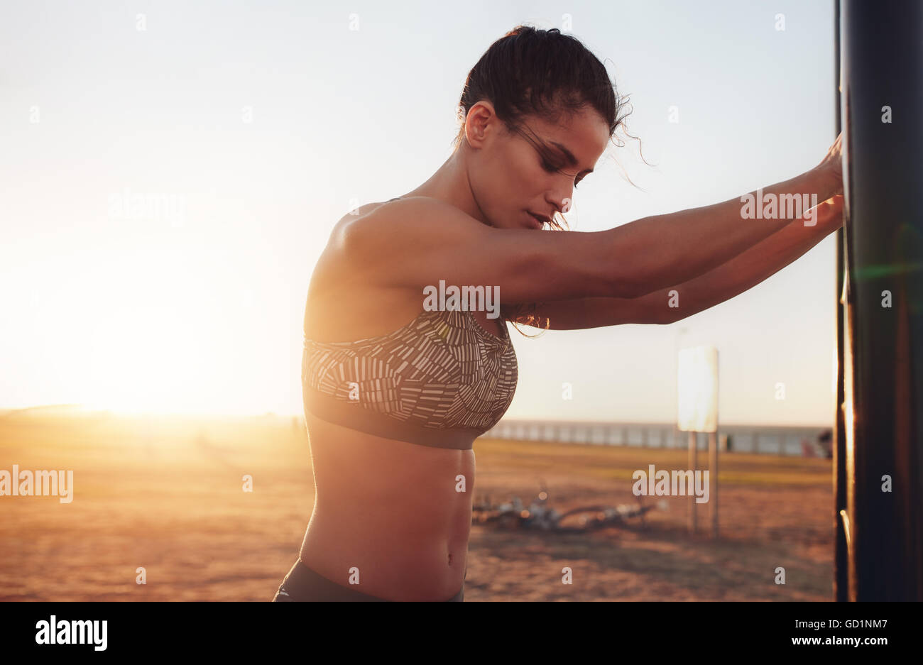 Schuss einer muskulösen jungen Frau mit Sport-BH, die draußen steht. Fitness-Frau, die eine Pause von intensiver Arbeit macht. Stockfoto