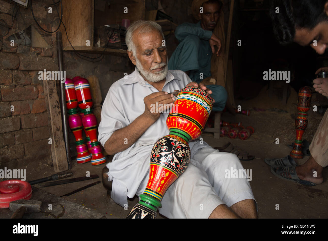 Ein Tischler macht farbenfrohe Designs und Blumen am Bein der Koje in seinem Geschäft in der Stadt von Pindi Bhatttian, Punjab, Pakistan. Stockfoto