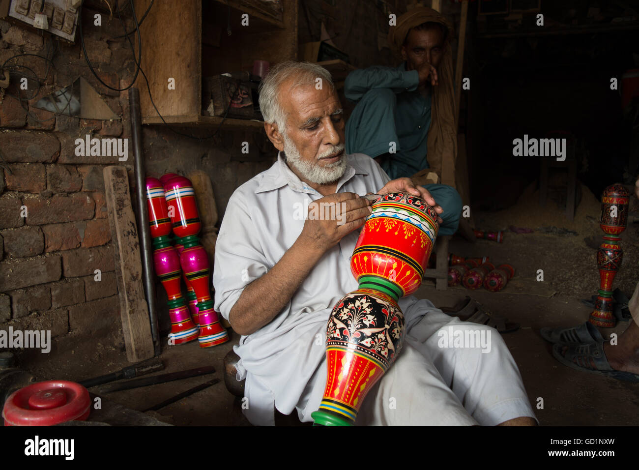 Ein Tischler macht farbenfrohe Designs und Blumen am Bein der Koje in seinem Geschäft in der Stadt von Pindi Bhatttian, Punjab, Pakistan. Stockfoto