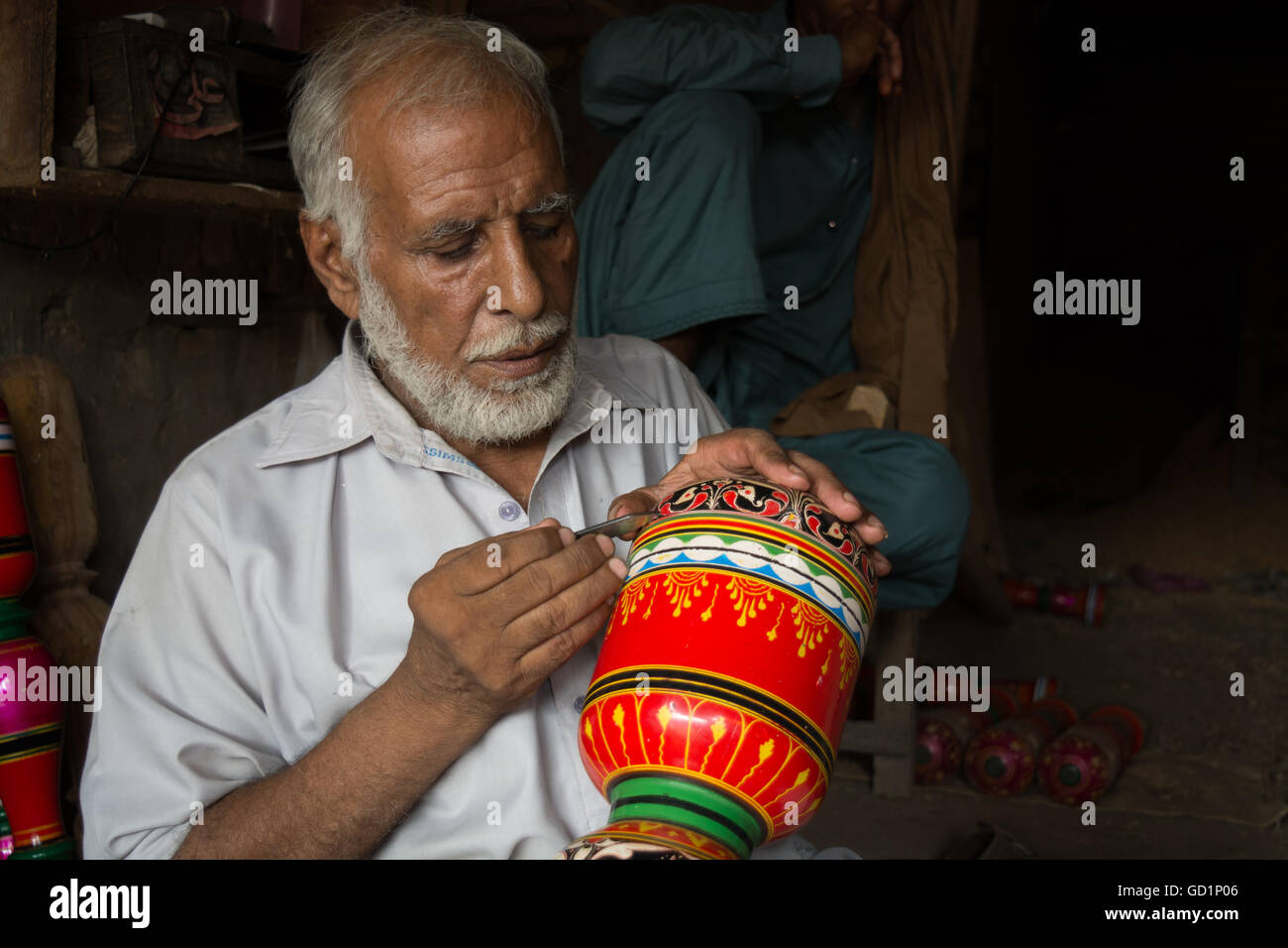 Ein Tischler macht farbenfrohe Designs und Blumen am Bein der Koje in seinem Geschäft in der Stadt von Pindi Bhatttian, Punjab, Pakistan. Stockfoto