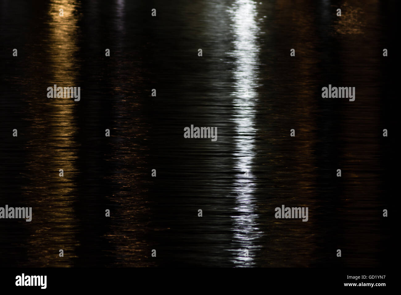 Reflexion von gelben und weißen Lichter in der Nacht auf dem Wasser in gelb und Silber schimmernden. Kurze Verschlusszeit. Stockfoto