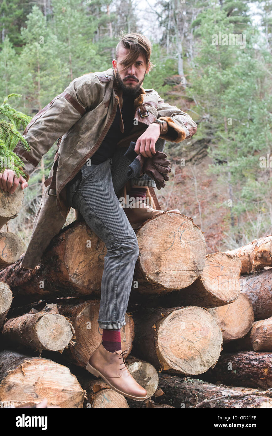 Junge Männer auf Baumstämmen im Wald. Leder und Jeans. Outdoor-Mode Stockfoto