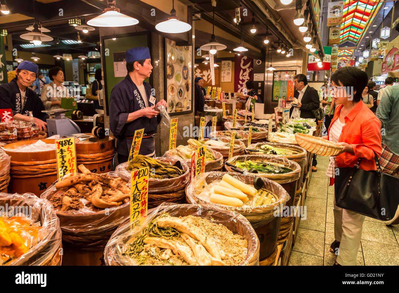 Shopper mit Korb hält Kauf bei lokalen japanischen Garküche, Nishiki Markt, Innenstadt von Kyoto, Japan, Asien Stockfoto